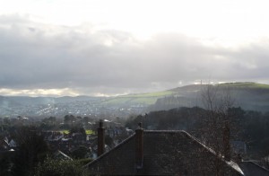 Greens slip through low clouds to gild a hilltop